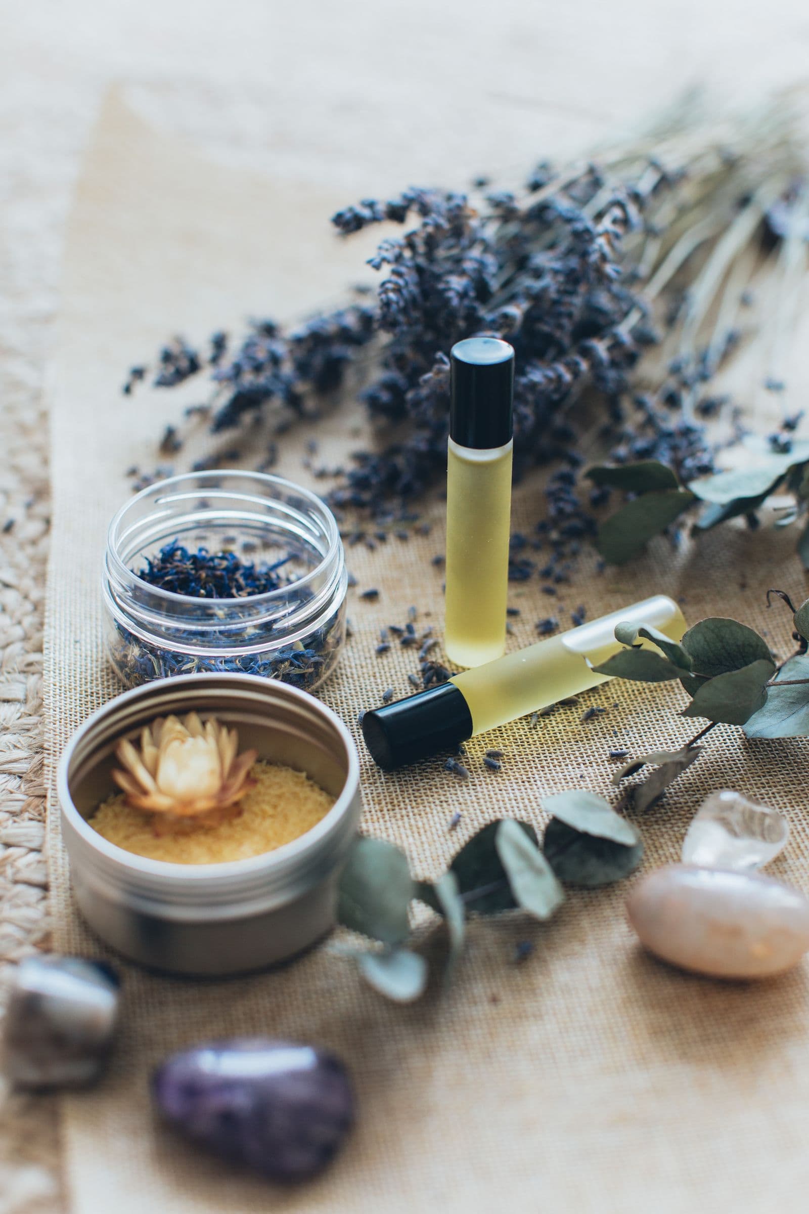 Lavender, sugar scrub, and aromatic oils arranged on natural linen