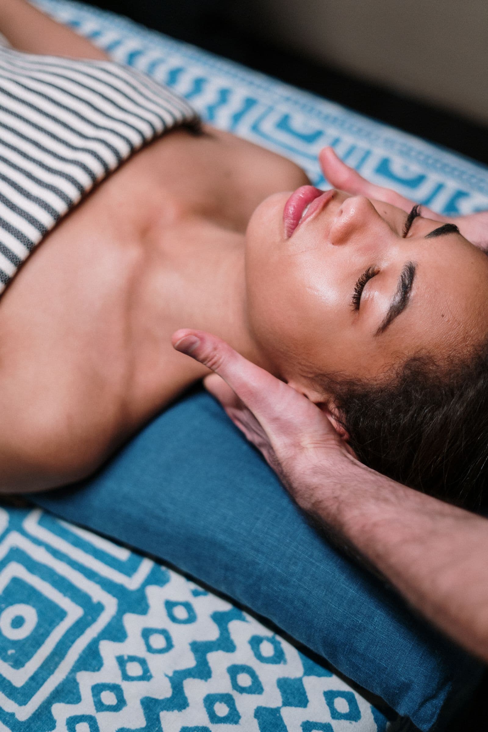 Therapist applying gentle acupressure to a relaxed guest's head and neck