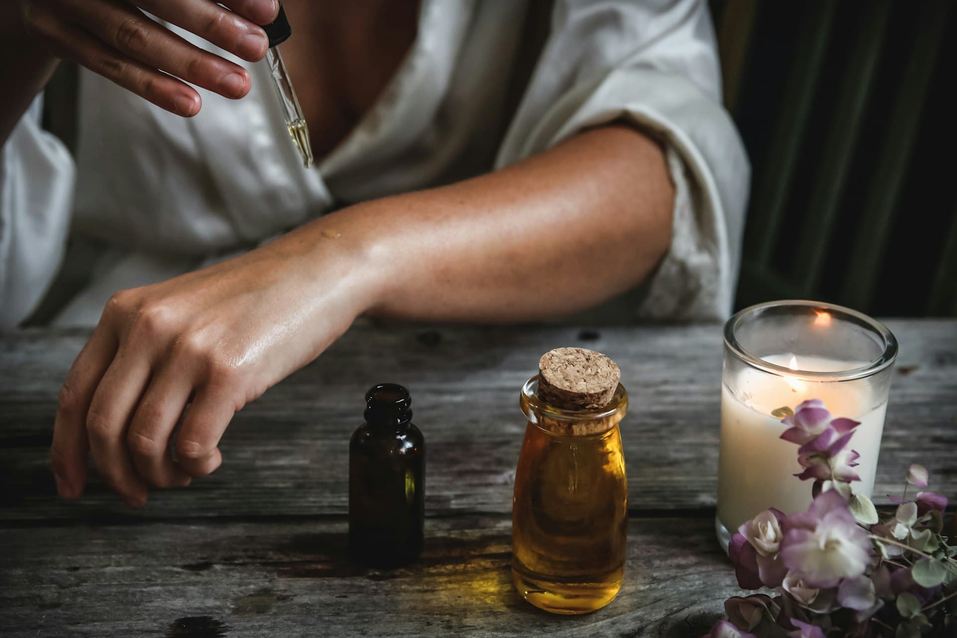Aromatic serum oils beside a softly lit candle